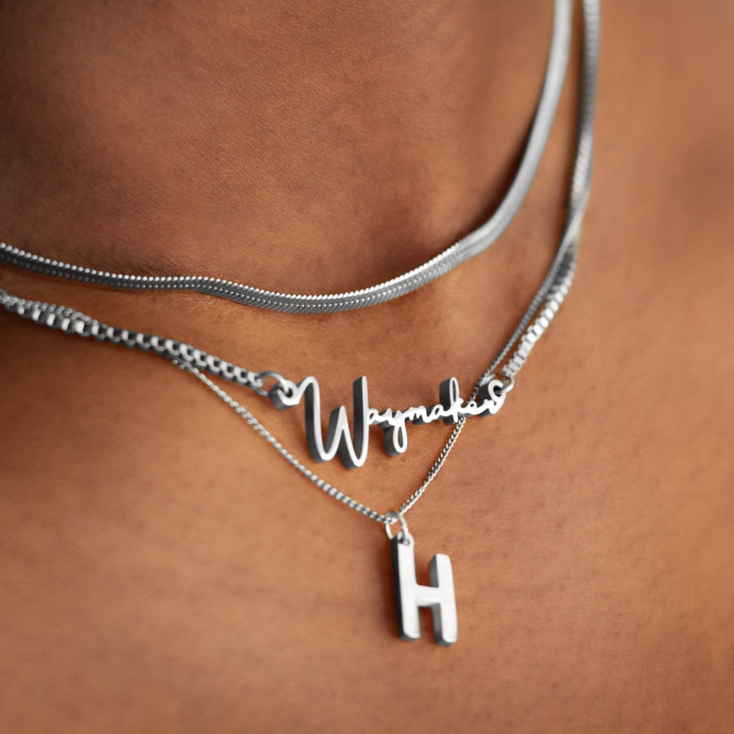 Front view of model layering the adjustable dainty cable necklace with other necklaces displaying its delicate chain and refined finish.