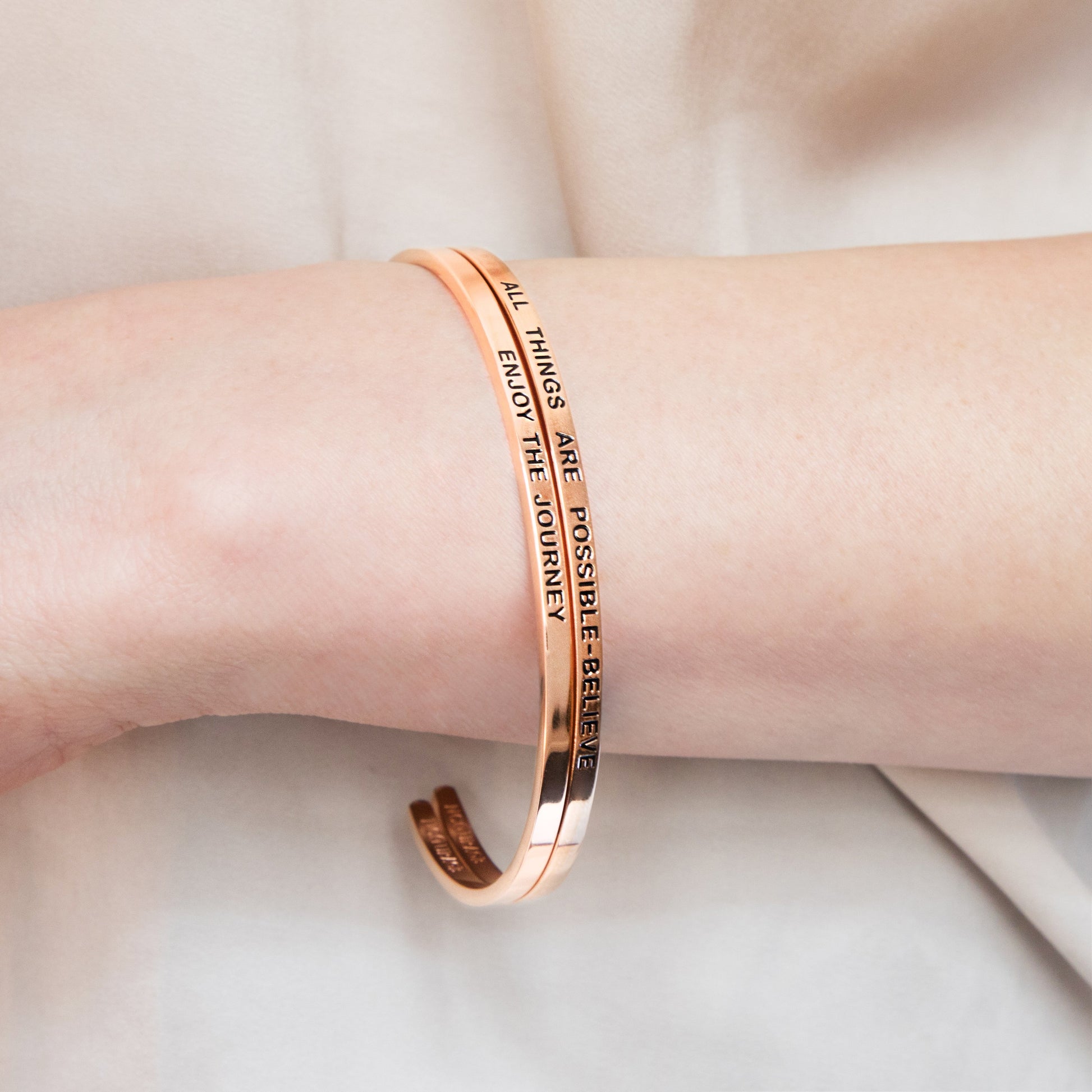 ALL THINGS ARE POSSIBLE - BELIEVE - bracelet  Lifestyle image of a model wearing the gold bracelet stacked with other bracelets, creating a stylish layered look.