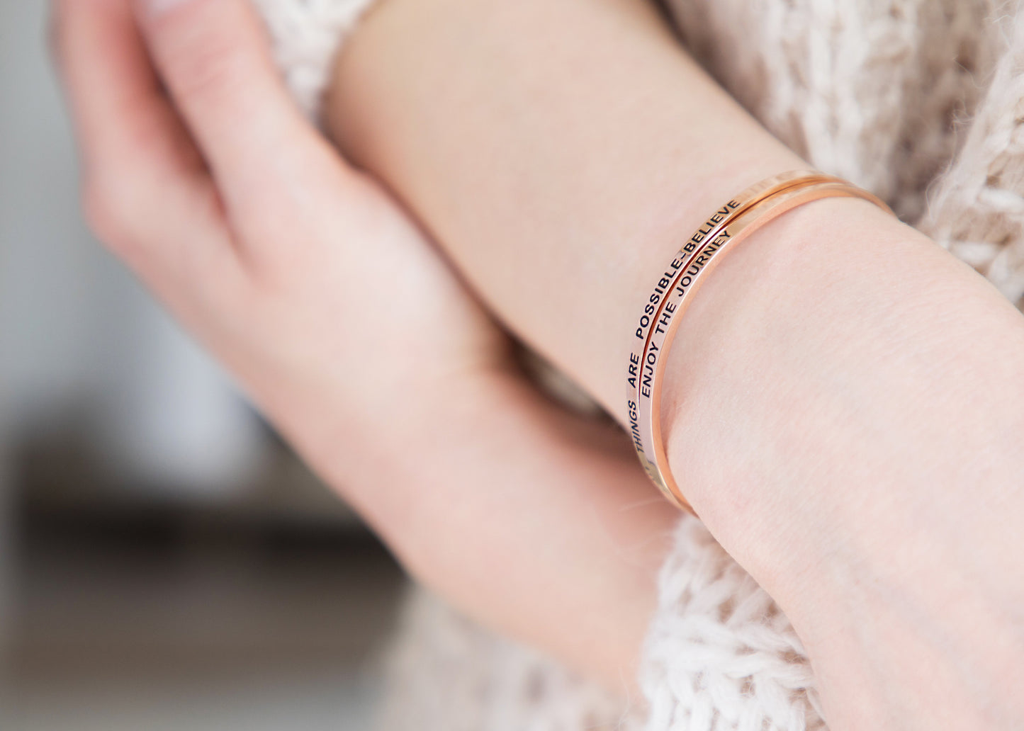 ALL THINGS ARE POSSIBLE - BELIEVE - NCOURAGE Bands and Bracelets  Lifestyle image of a model wearing the gold bracelet stacked with other bracelets, creating a stylish layered look.